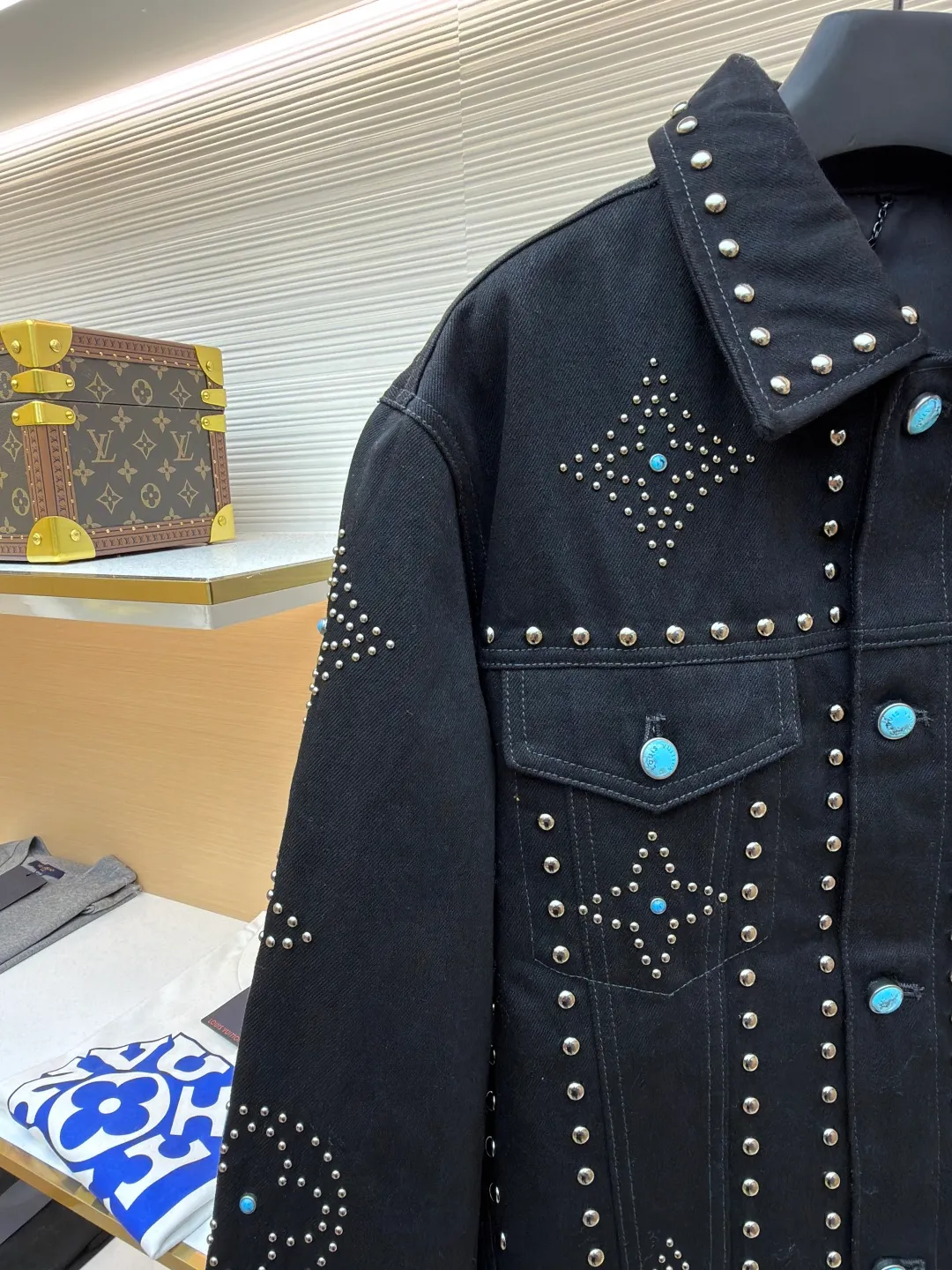 LOUIS VUITTON turquoise rivet denim jacket ●Original version: purchased and developed by 38979 ●Item number: 1682224-E30 ●Material: denim fabric ●Technology: hand-made rivet inlay ●Color: black ●Version: fitted version ●Weight: about 1550 grams ●Size: 46-48-50-52 ●Description: This black denim jacket is made of high-density twill denim fabric and has been treated with pre-washing water. It not only retains the crisp texture of the fabric, but also achieves a soft and skin-friendly wearing experience. The entire body of the garment is made of hand-made rivet inlay technology. The metal rivets are arranged at precise points to outline the outline of the brand's classic logo. Each rivet is manually hammered and fixed to ensure firmness and three-dimensionality. The placket and pockets are decorated with turquoise-textured resin buttons, which contrast with the metal rivets. The stitching on the collar, cuffs and hem adopts a double stitching process to enhance structural stability, while the edges are roughened to add a retro texture. The overall cut is a slightly loose Oversize version, combined with the three-dimensional tailoring process of the three-dimensional shoulder line, taking into account both styling and wearing comfort. Every detail is calibrated by hand, demonstrating the exquisite level of clothing making technology. The overall wiring is straight and delicate, the fabric is comfortable and soft, and the color is consistent without color difference. It can be matched with the same style to create a fashionable look and control various occasions. Customized accessories, complete with three standards, same style for men and women!
